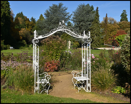 Kleiner eiserner Bogen als Eingang zu einem Garten mit Sitzplätzen