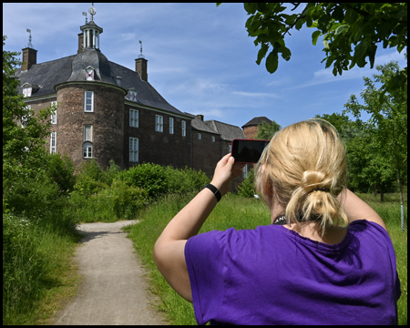 Eine Frau fotografiert mit dem Handy das Schloss Ringenberg 
