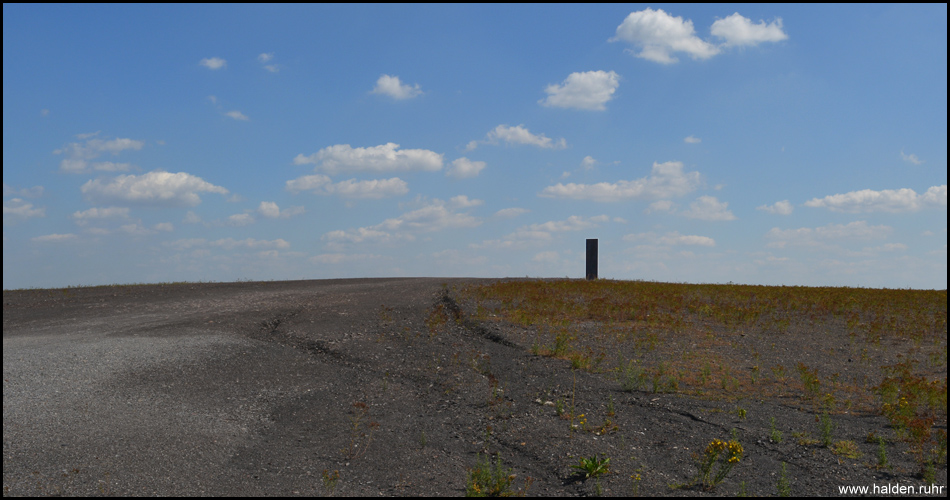 Der größtenteils unbewachsene Gipfel wirkt wie eine Mondlandschaft. In der Mitte steht die Landmarke "Bramme für das Ruhrgebiet"