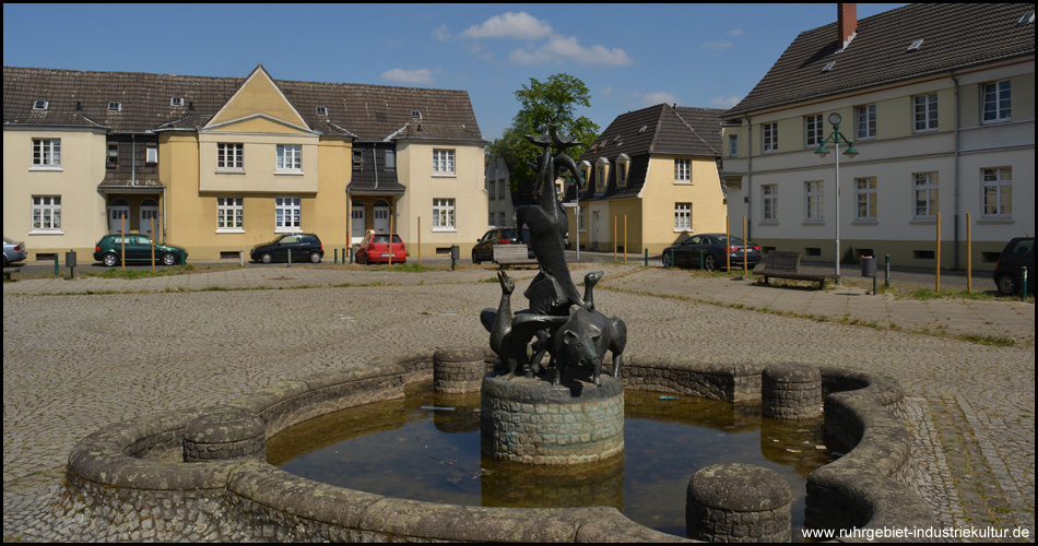 Namensgebender Brunnen auf dem Platz vor dem Uhrenturm mit Schwein, Ziege, Gänsen und Tauben