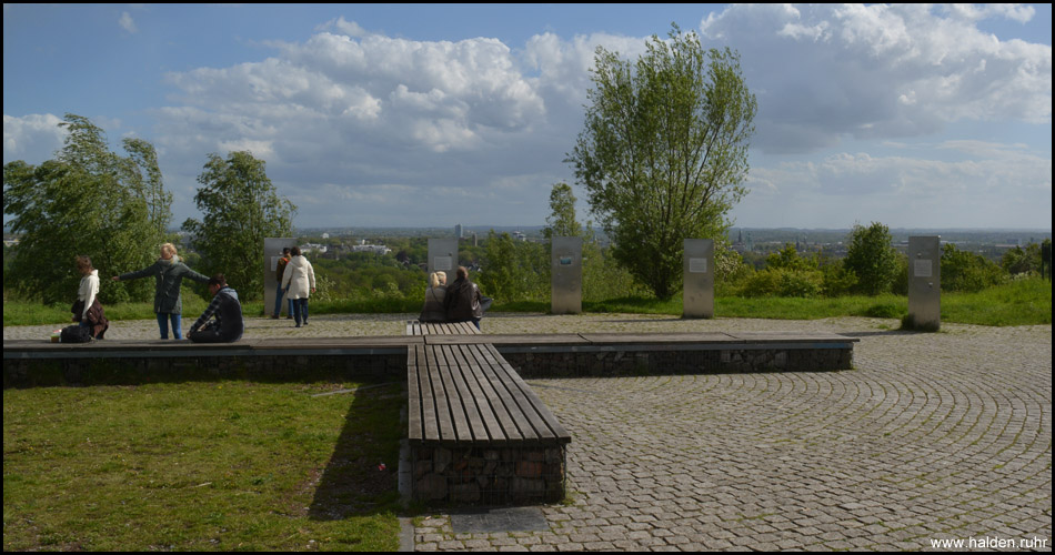 Liegendes Gipfelkreuz als Sitzgelegenheit am höchsten Punkt und Panoramablick auf Bochums Innenstadt