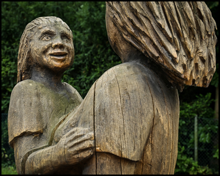 Skukptur aus Holz mit einer Frau, die ein Kind trägt