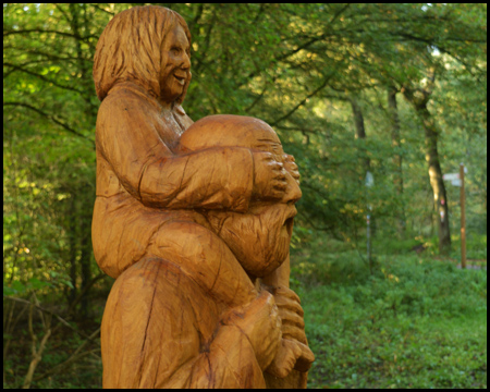 Holzskulptur mit einem Mann, der ein Kind auf den Schultern trägt