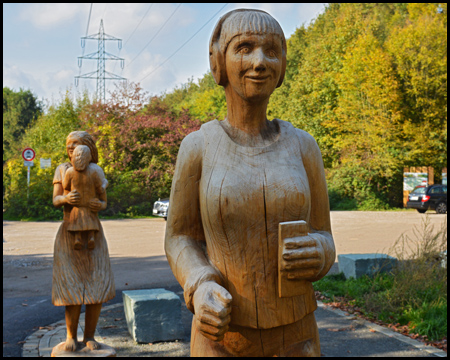 Holzskulptur einer Frau mit einem Smartphone in der Hand