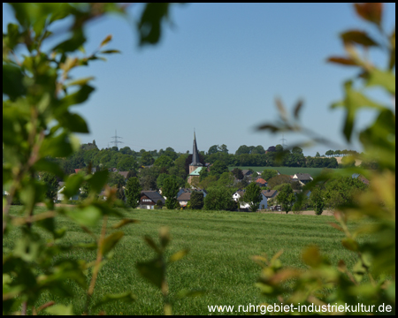 Blick durch die Feldhecke auf die Johanneskirche Frömern