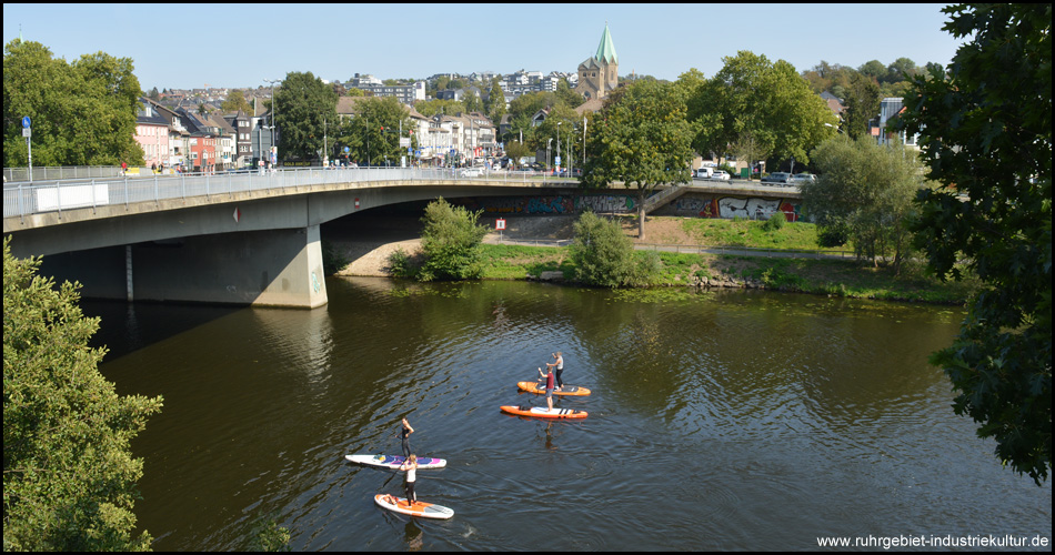 Stehpaddler auf der Ruhr an der großen Brücke in Werden. Hinten ist die Abteikirche zu sehen