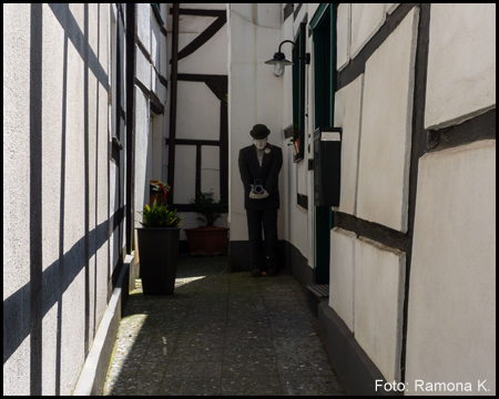 Eine Gasse zwischen zwei Fachwerkhäusern mit einer Kunstfigur