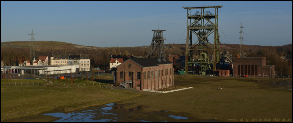 Blick auf Zeche, Stadtteilpark und Einkaufszentrum, hinten Deponie Nordost. Diese Ansicht ist inzwischen im Vordergrund zum Teil verbaut. Vorne Maschinenhalle und Tomson-Bock von Schacht II, dahinter der Doppelbock mit den zwei Maschinenhäusern über Schacht IV 