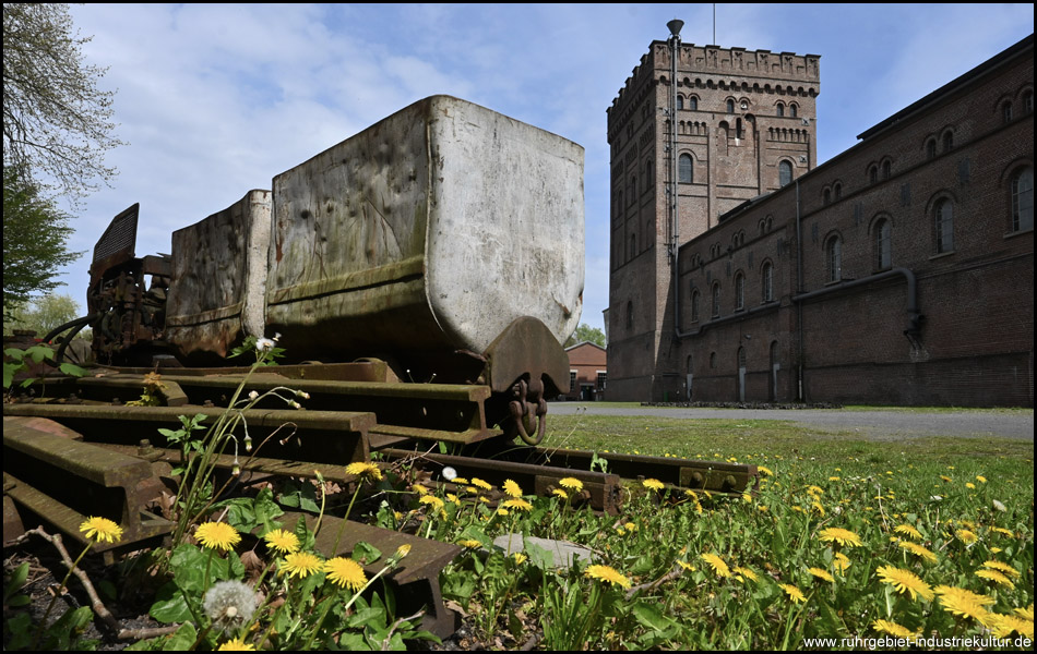 Eine alte Lore steht als Ausstellungsstück vor dem Malakowturm der Zeche Hannover in Bochum