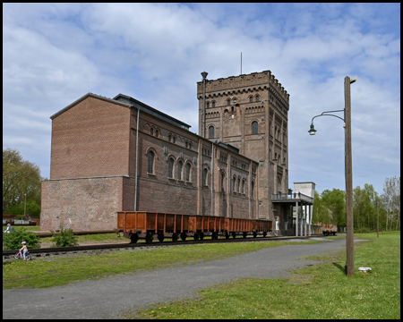 Eisenbahnwaggons vor Maschinenhalle und Malakowturm der Zeche Hannover