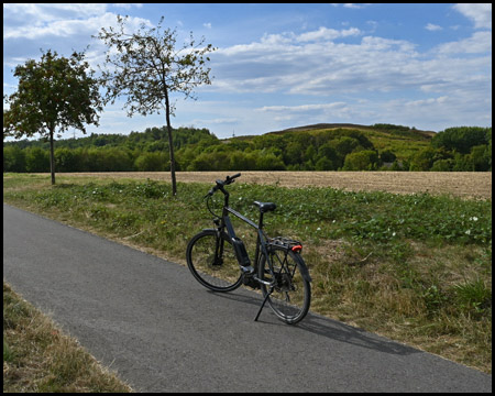 Fahrrad auf dem Radweg, im Hintergrund eine Halde